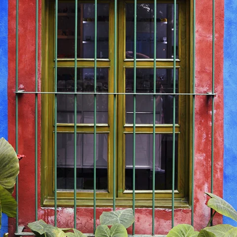 A large window with gold panes on a blue and red house 