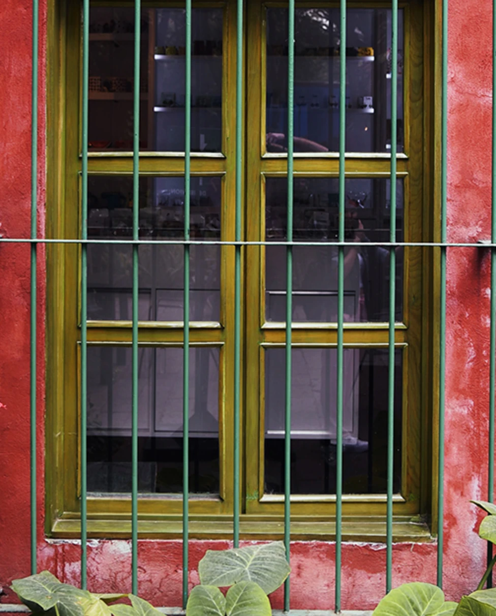 A large window with gold panes on a blue and red house 