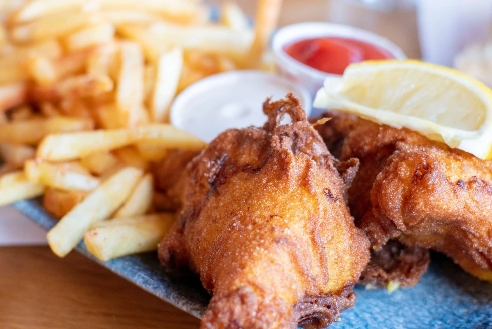 Fried fish and french fries with a lemon on a blue plate