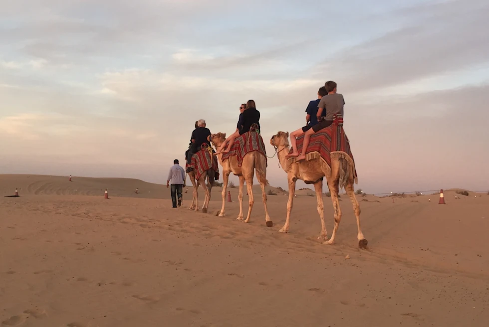 a family riding on camelback in the desert