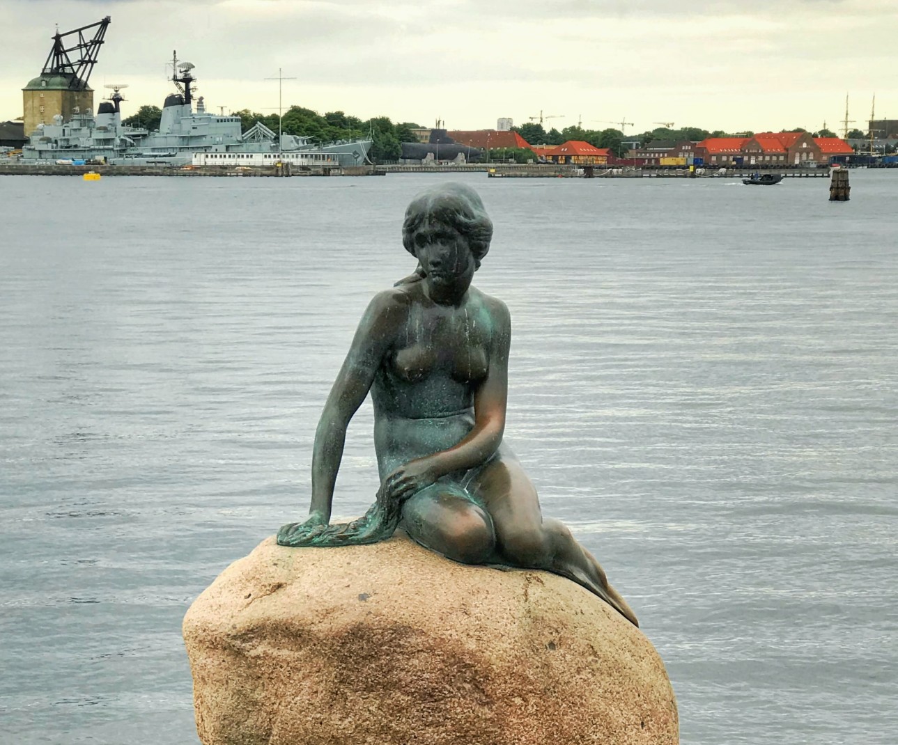 Statue on rock next to body of water during daytime