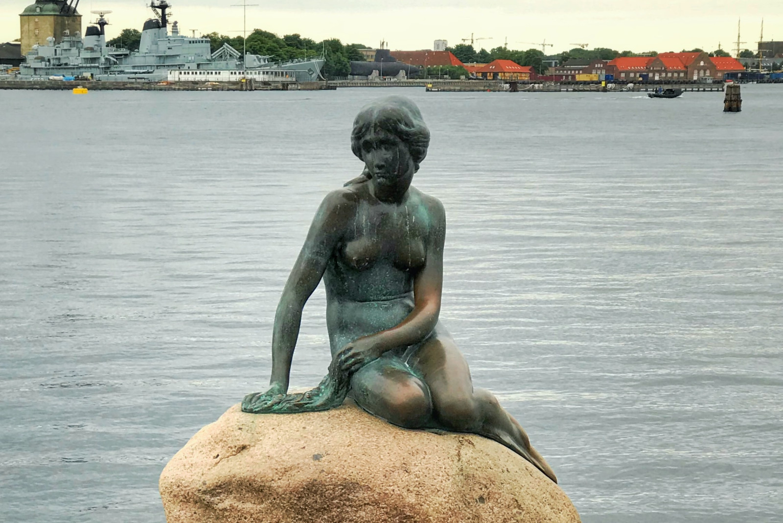 Statue on rock next to body of water during daytime