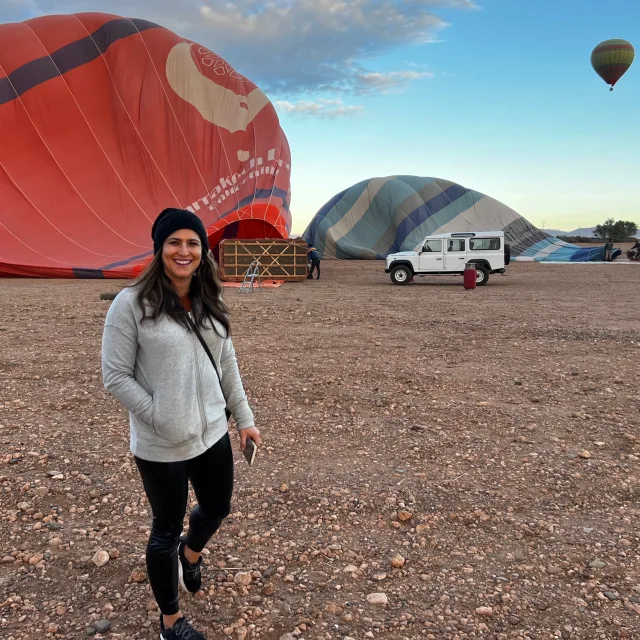 Travel Advisor Desiree Knight standing in dirt with hot air balloons in the background.