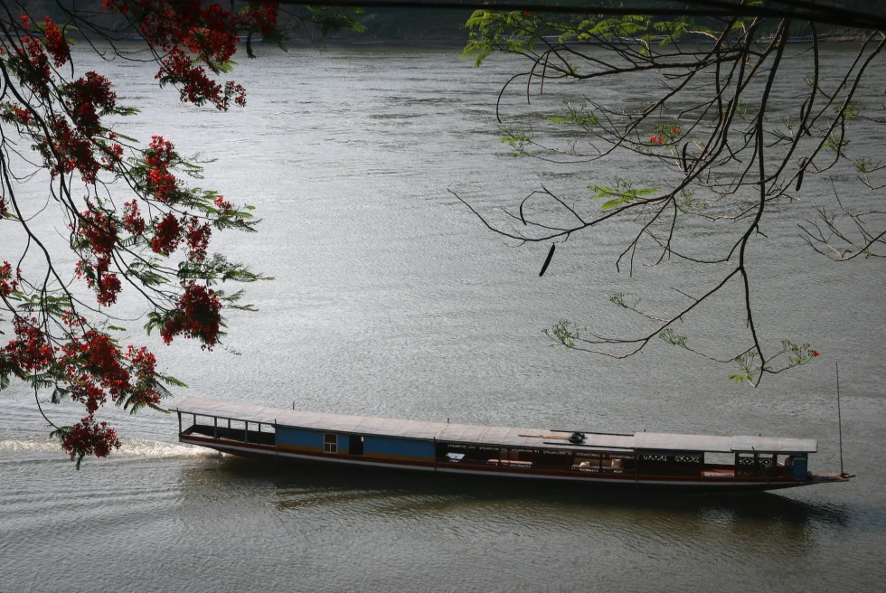 A long boat sailing in a river. 