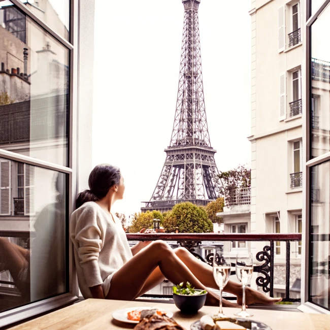 Woman looking at the Eiffel Tower from her hotel room