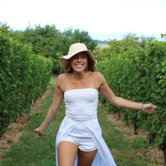 Travel Advisor Isabel Smallman walking through vineyards in an all white outfit with a tan hat.