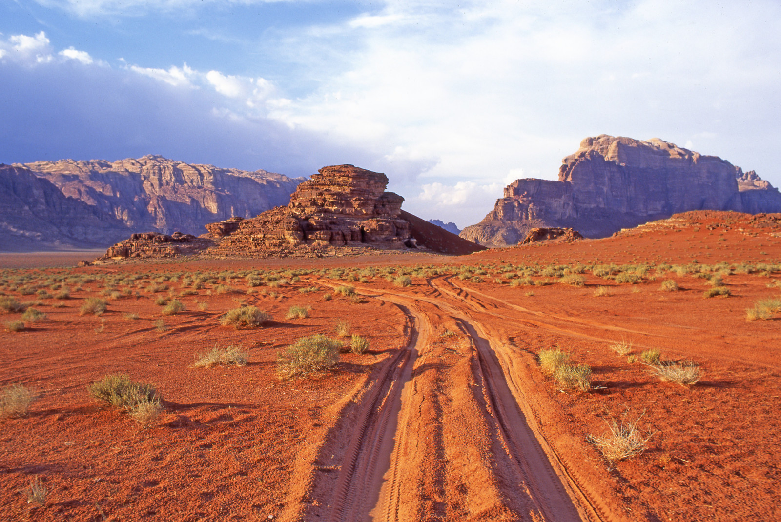 Red dirt roads leads to striking red cliffs in Wadi Rum, Jordan
