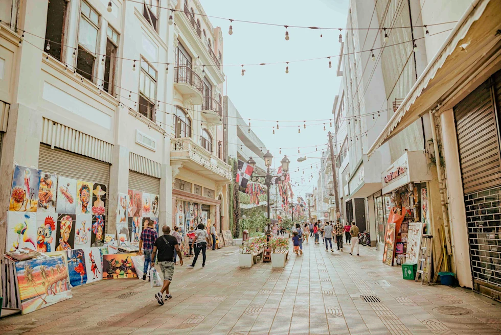 Street in Santo Domingo with people walking and a vendor selling colorful paintings