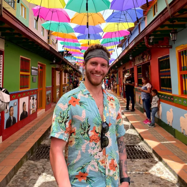 Travel advisor Brandon Lomasney in a bright-colored shirt and a headband under colorful umbrellas