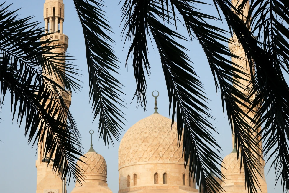Jumeirah Mosque with trees in the foreground with a blue sky