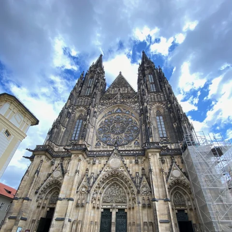 The amazing architecture of St. Vitus Cathedral in front of clouds and a blue sky.