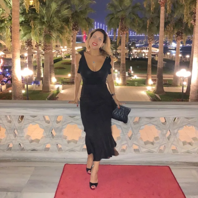 Travel advisor Mariana Toledo standing in front of palm trees in a black dress.