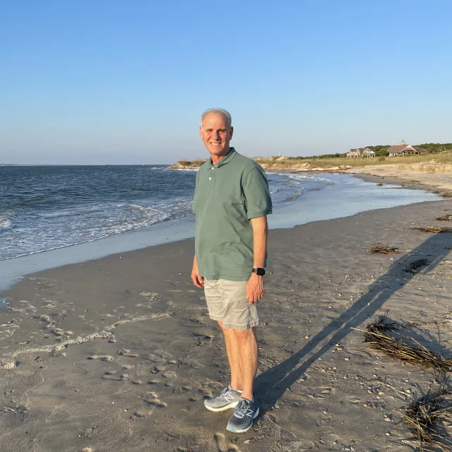 Travel Advisor Richard Ditaranto on a beach with a green shirt and khaki shorts.