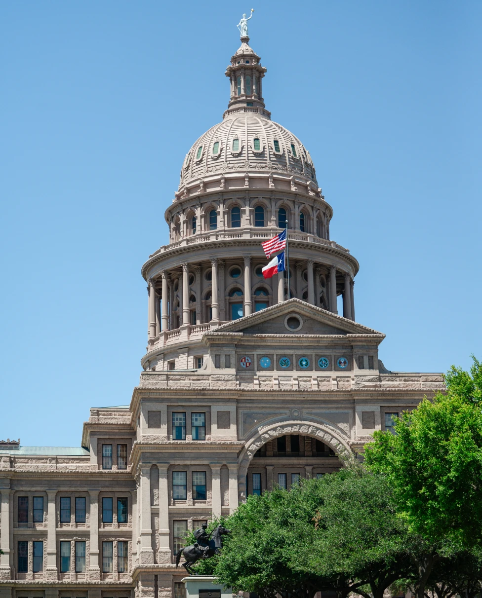 Capitol building with grass and flags with blue sky in Austin, Texas