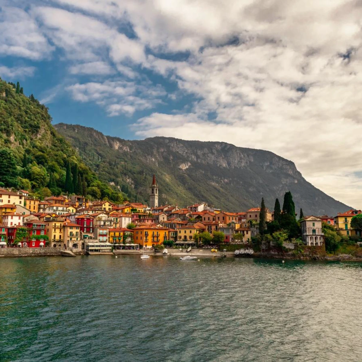 Sea side Italian town, Lake Como in front of mountains on a cloudy but sunny day.