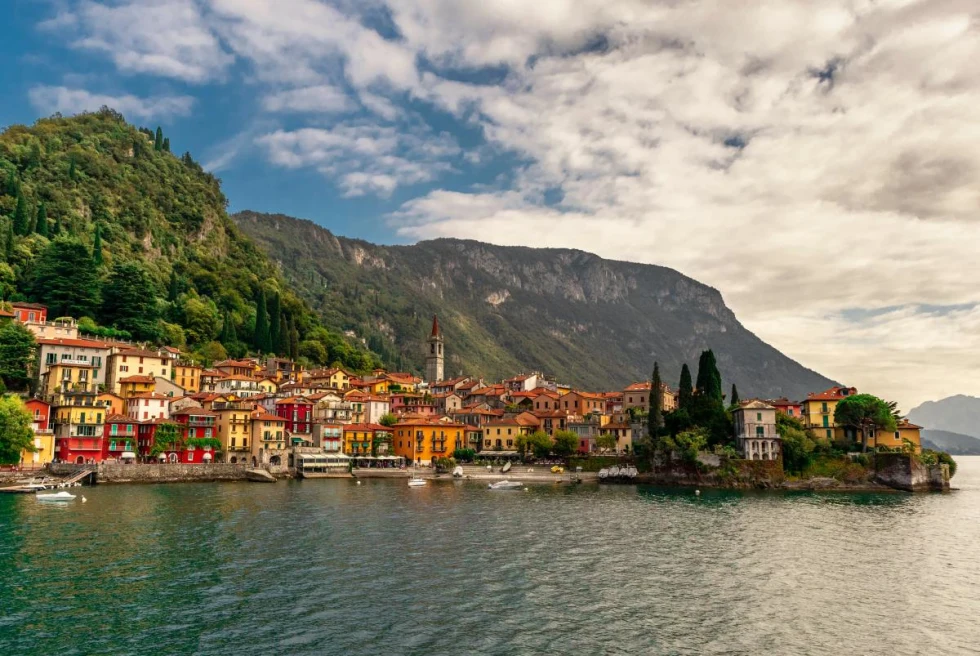 Sea side Italian town, Lake Como in front of mountains on a cloudy but sunny day.