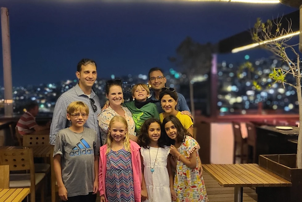 A family standing in a restaurant's outdoor sitting at night time.