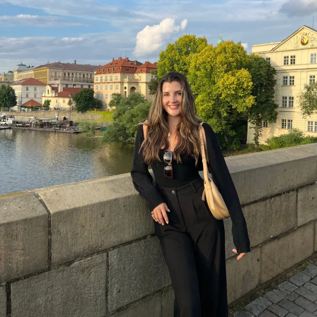 Travel Advisor Isabelle Sichler in an all black outfit in front of a river and colorful houses.