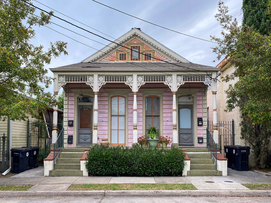 pink house in new orleans with green bushes and trees 