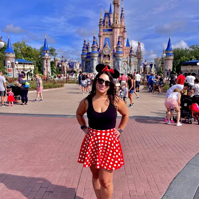 Fora travel agent Sherri Herrera wearing red skirt with Disney castle in background