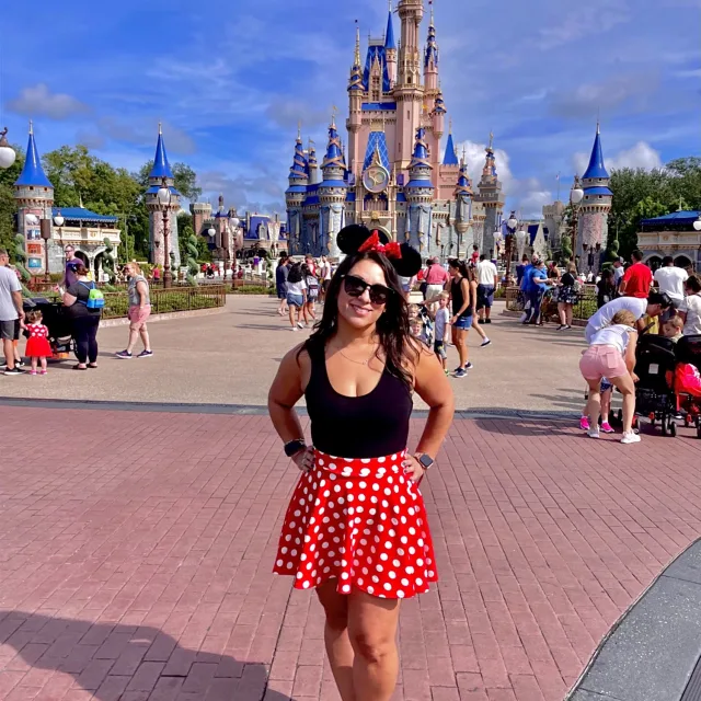 Fora travel agent Sherri Herrera wearing red skirt with Disney castle in background