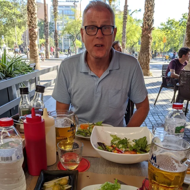 Travel Advisor Daryl Bruner with a blue shirt and black glasses sitting in front of a table of food.