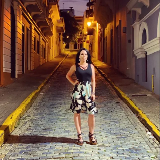Travel Advisor Leslie Bennett in a black shirt and floral skirt standing on a cobblestone street