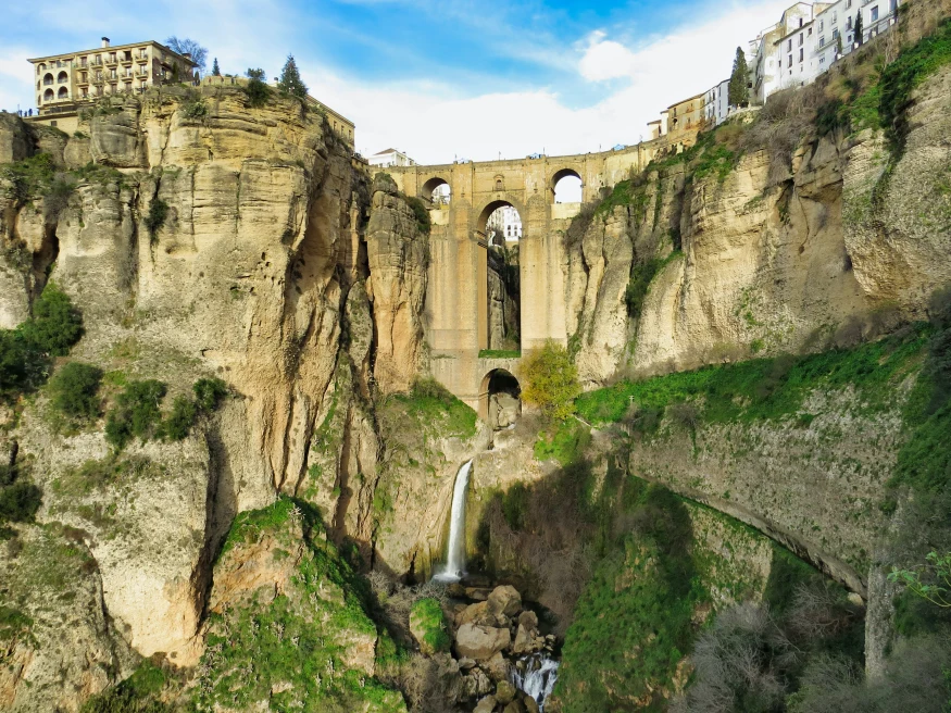 bridge with waterfall beneath it during daytime