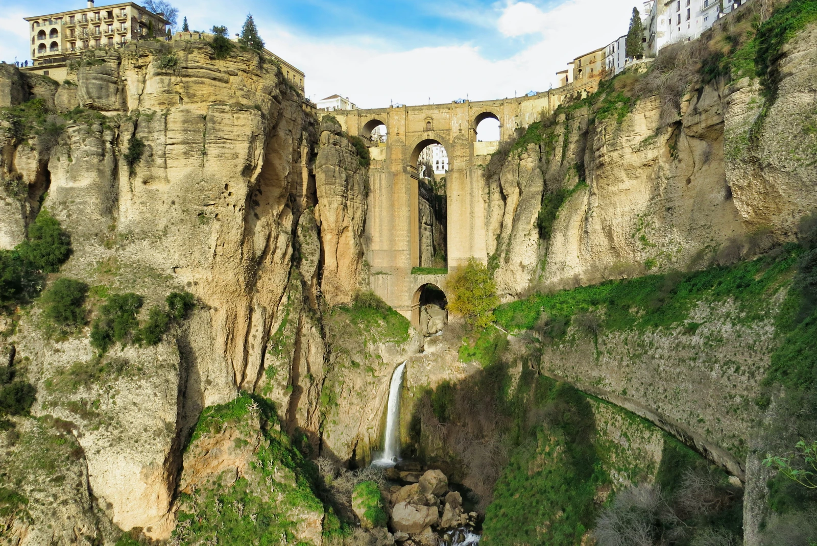 bridge with waterfall beneath it during daytime
