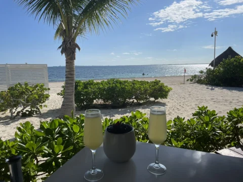 Three drinks on a table looking out on to the beach during the daytime