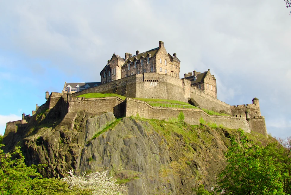 large castle perched on a green hill on a cloudy day