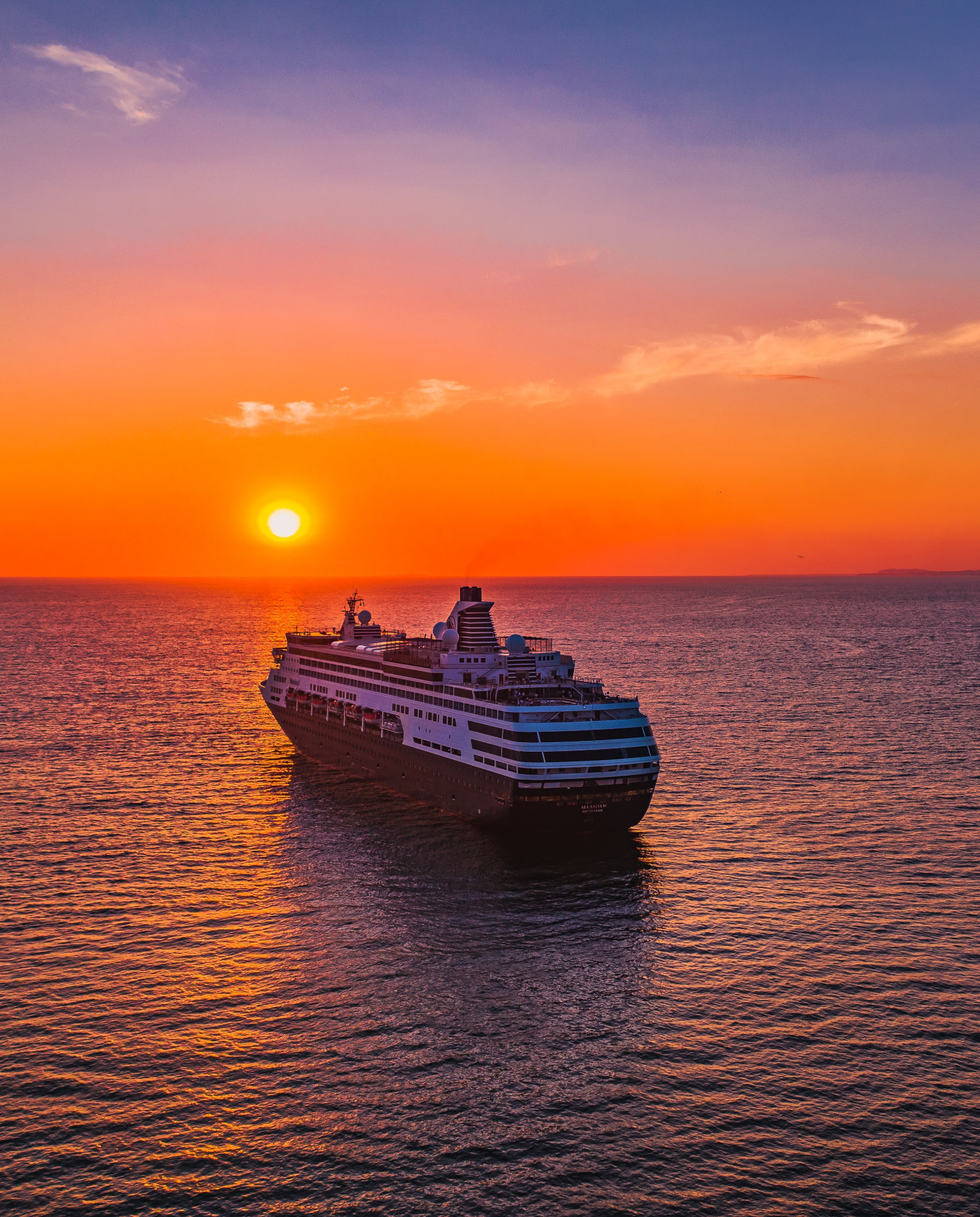 cruise ship in large body of water during sunset