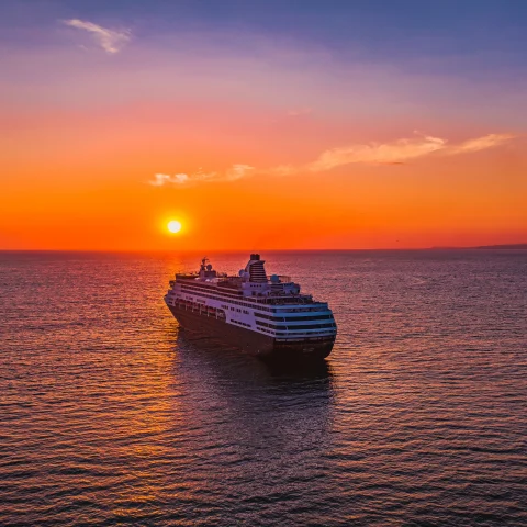 cruise ship in large body of water during sunset