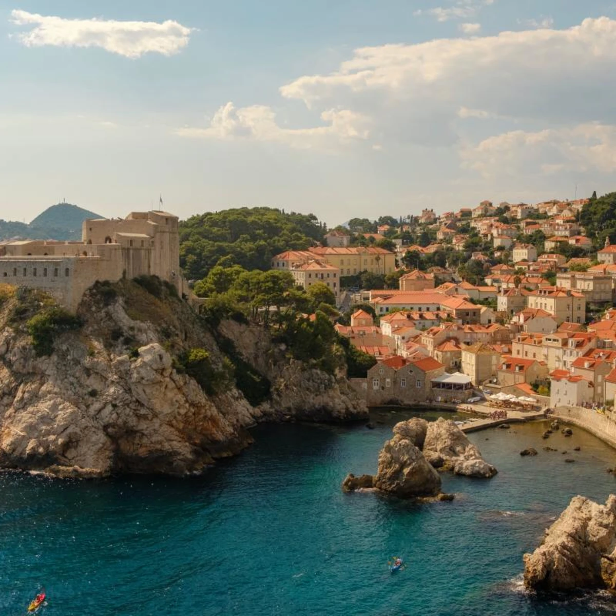 Croatia coast flanked by a cliff dotted with red and white clay and stone buildings 
