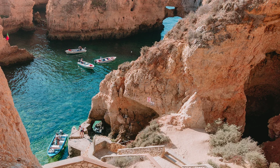 Lagos Portugal red cliffs and four boats over clear blue water