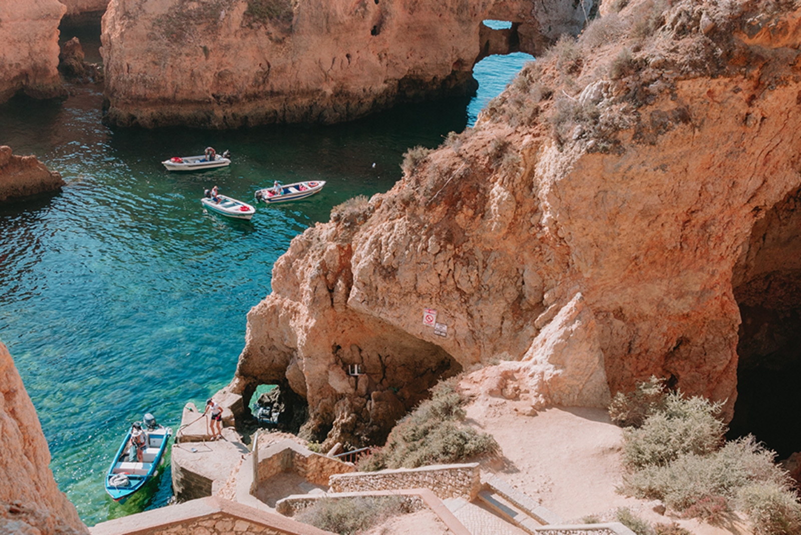 Lagos Portugal red cliffs and four boats over clear blue water