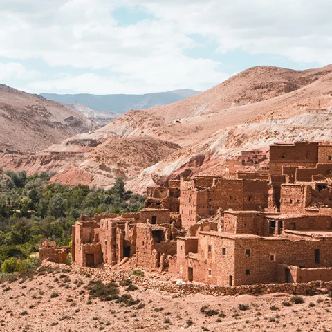 Morocco Marrakech red clay houses with hills and patch of green trees and bushes