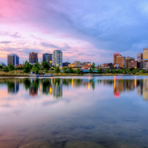 A city reflected in a lake during a blue and purple sunset