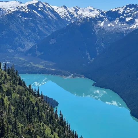 a light blue lakes runs though large mountain range