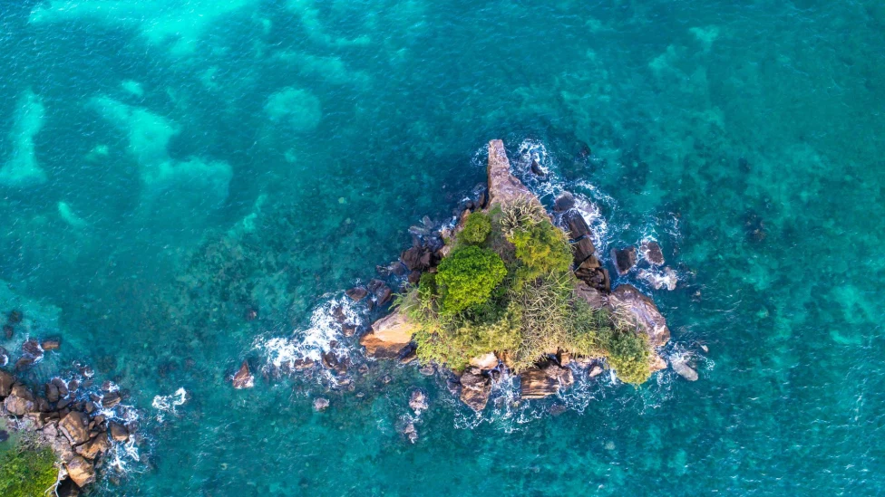 aerial view of a lush islet in a turquoise sea
