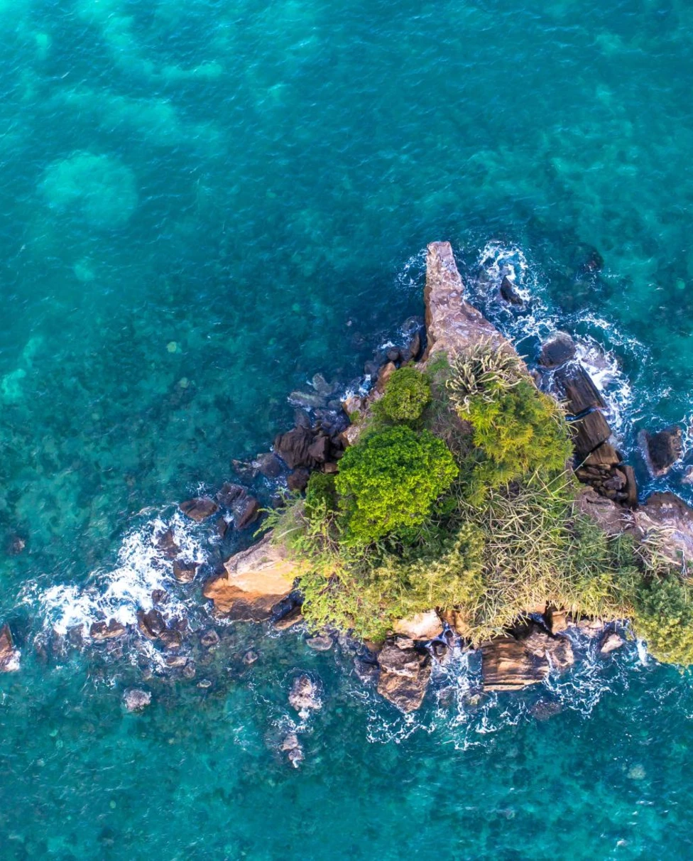 aerial view of a lush islet in a turquoise sea