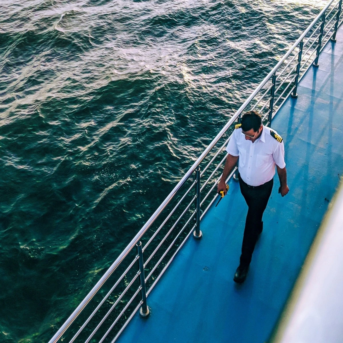Aerial view of man walking on cruise ship next to body of water during daytime