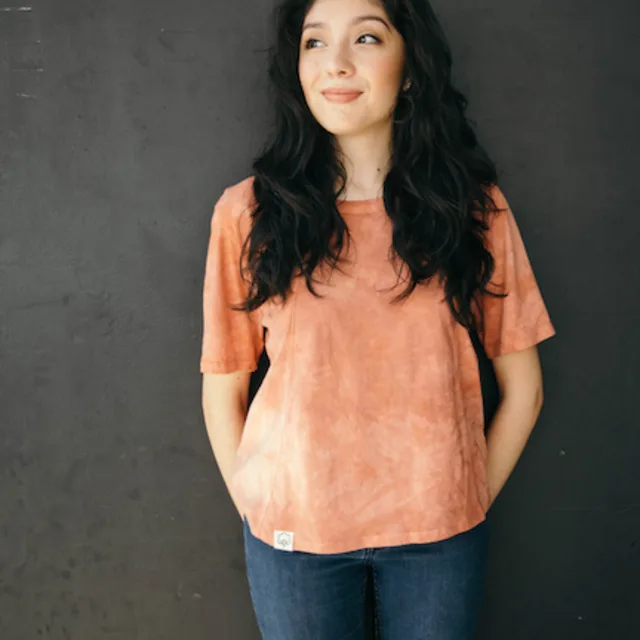 woman wearing orange shirt standing in front of a black wall