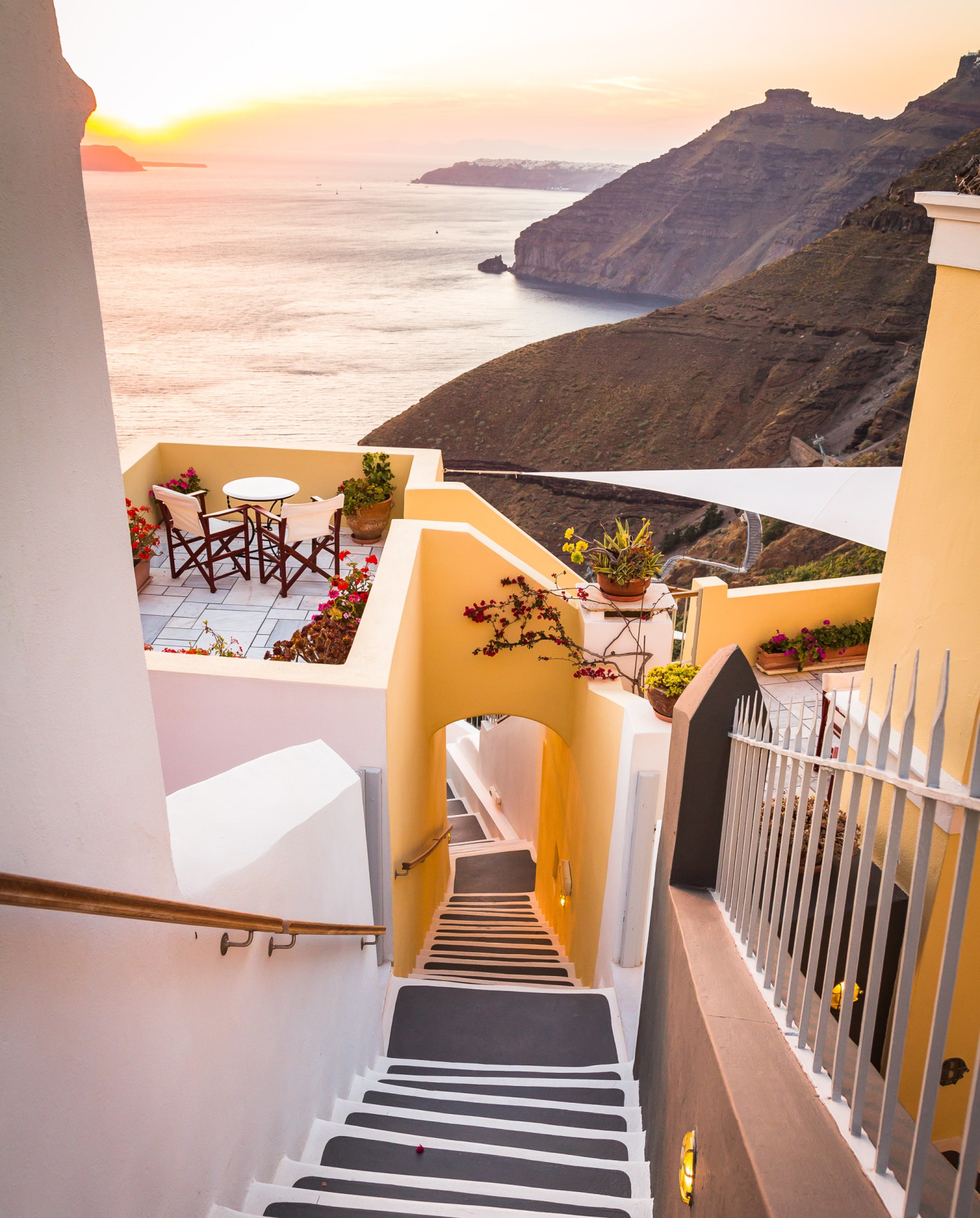 A white-washed staircase flanked by buildings in front of the Mediterranean in Greece. 