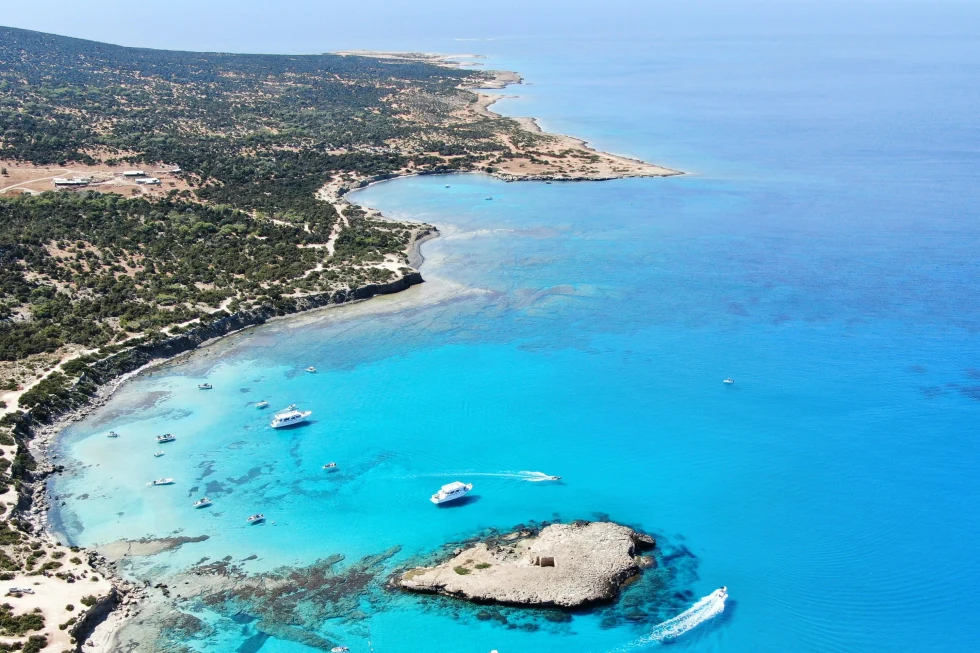 An aerial view of a beach with clear blue water. 