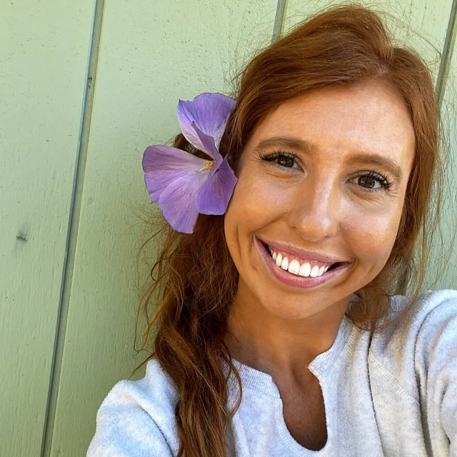 Travel Advisor Jillian Bucherl in a white top and lilac flower behind her ear.