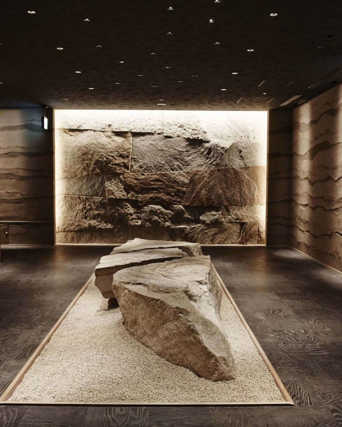 a dimly lit dining room with a large stone in the middle and stone walls