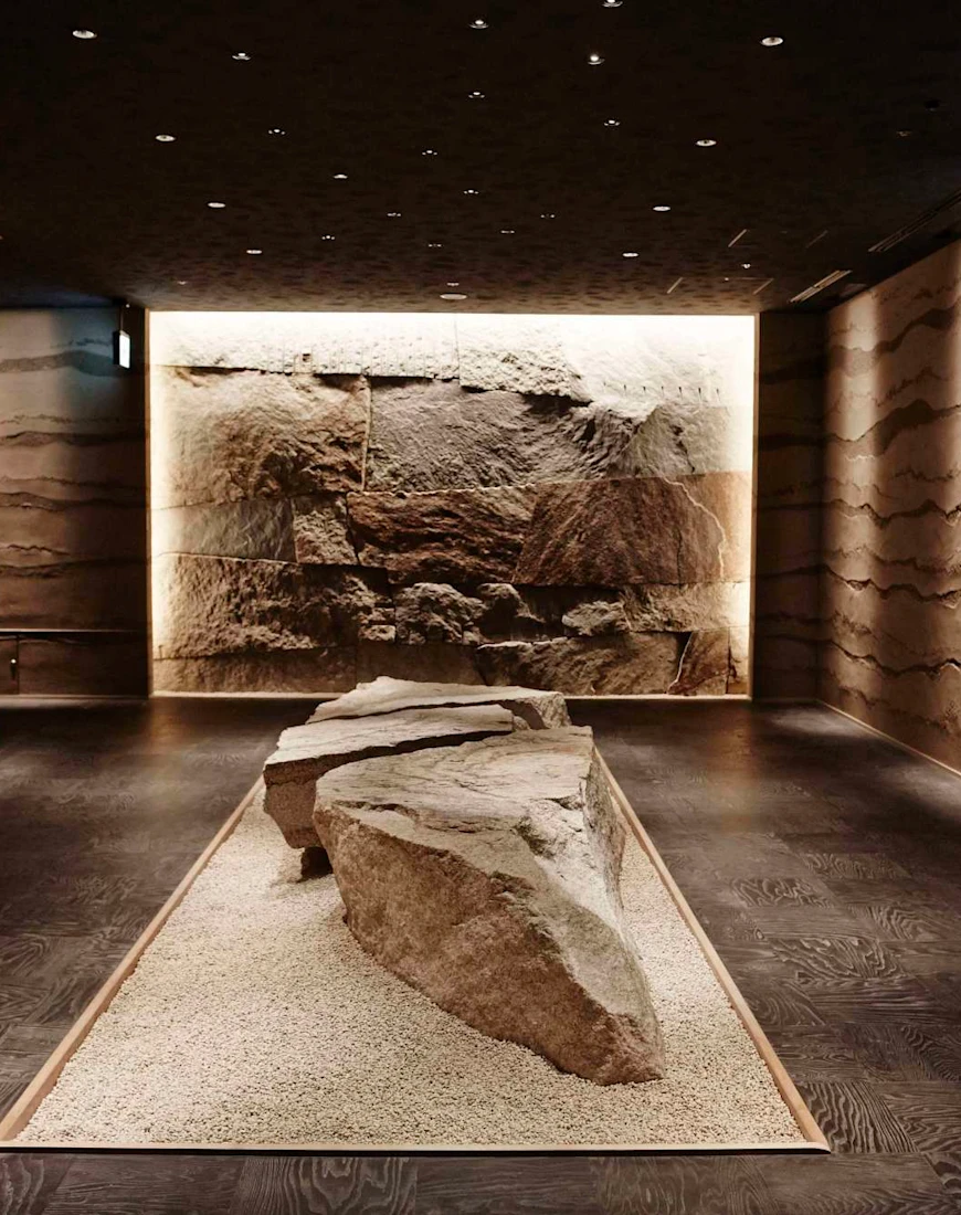 a dimly lit dining room with a large stone in the middle and stone walls