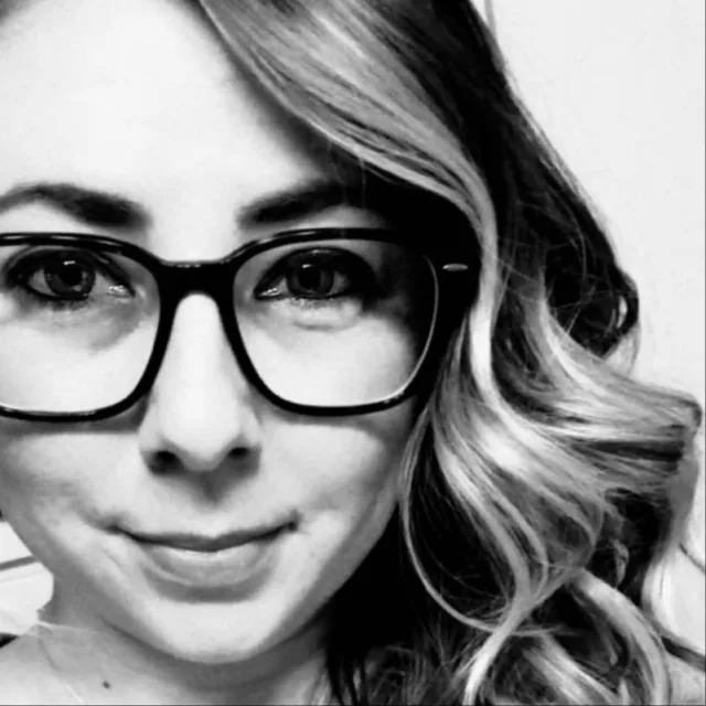Up-close black-and-white shot of travel advisor Samantha Perdick in black glasses