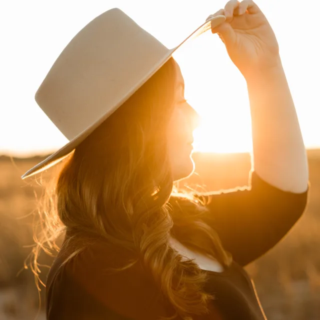 Ellie Warden wearing a hat with the sunset shining through in the background